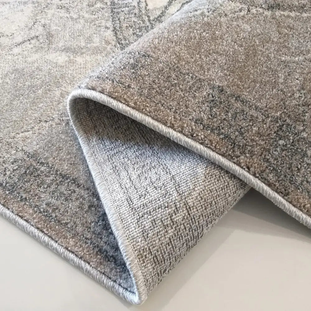 Teppe Vista 04, nærbilde av grå og beige tekstur, viser tette kanter og teppets underside tydelig.