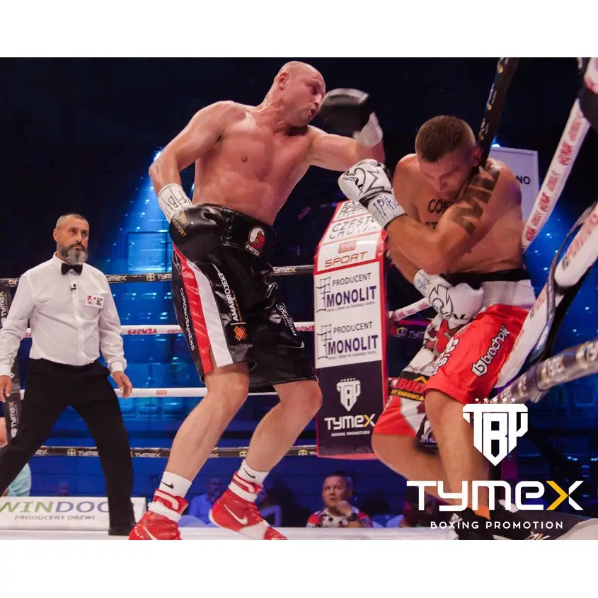 TIGER BLACK V 14 oz boksehansker i bruk under boksekamp, én bokser slår mens motstanderen dekker seg mot tauene.