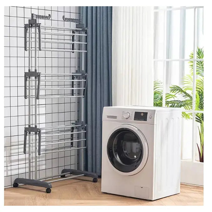 Tørkestativ for klær XXL i sølvfarget metall, sidevisning med flere hyller ved hvit vaskemaskin.