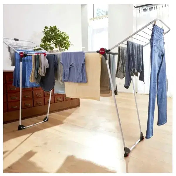 Tørkestativ for klær XXL Vileda Infinity 3M, sidevisning med blå og beige klær til tørk på lyst tregulv.