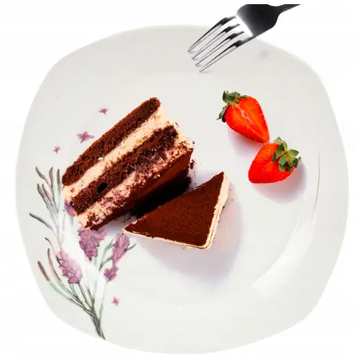 Hvit porselenstallerken med blomstermotiv, servert med sjokoladekake, jordbær og gaffel, sett ovenfra.