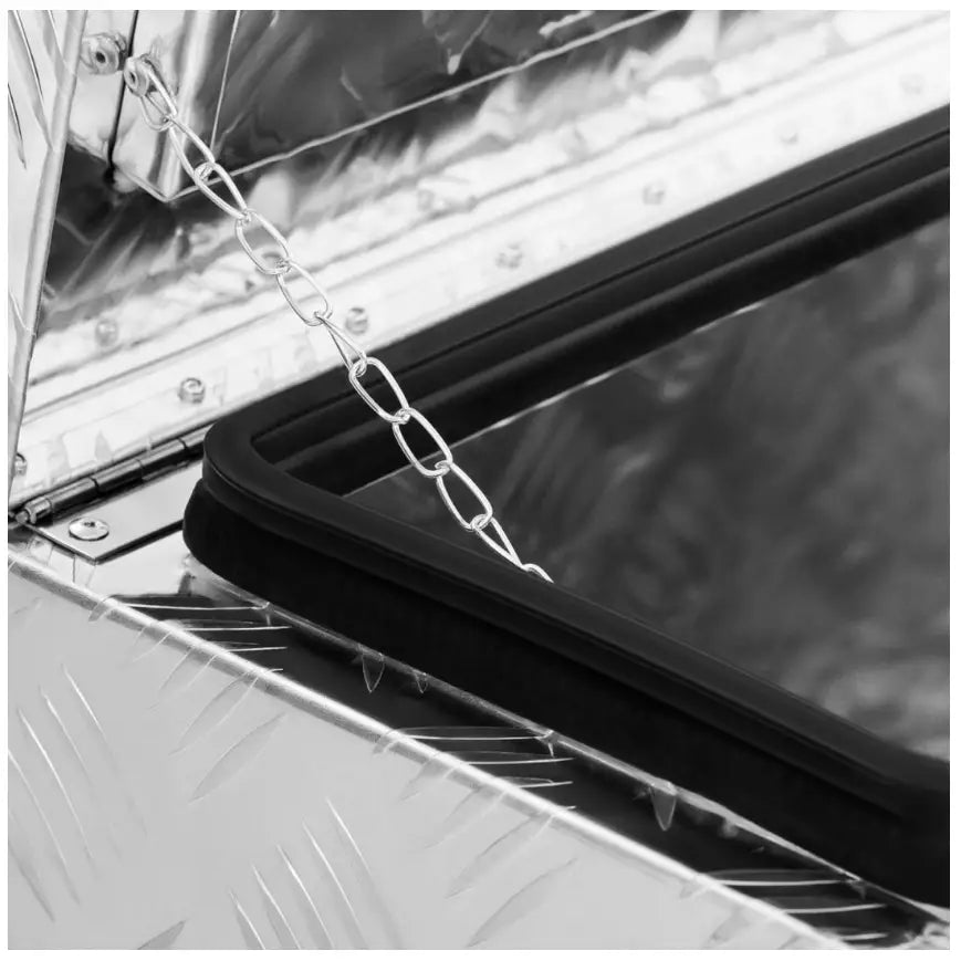 Transportabel verktøykasse i aluminium, nærbilde av åpent lokk med diamantmønster, støttekjede og gummipakning.