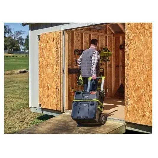 Transporttralle fra Ryobi sett bakfra, fylt med oppbevaringsbokser, trilles inn i skur via rampe i dagslys.