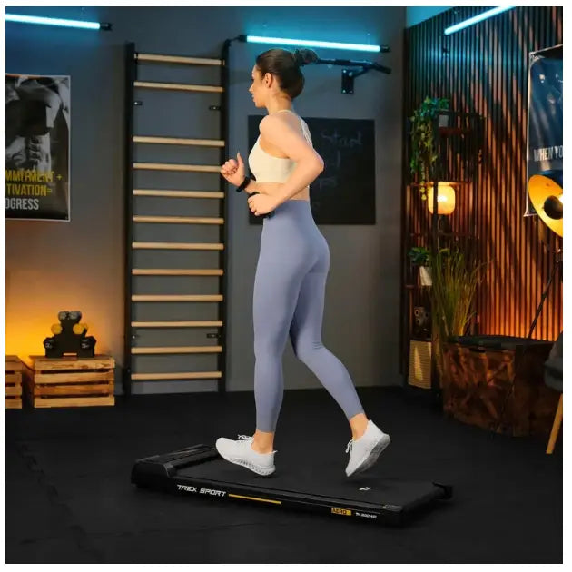 Tredemølle for hjemmetrening AERO Trex Sport, sidevisning med joggende kvinne i moderne treningsrom.