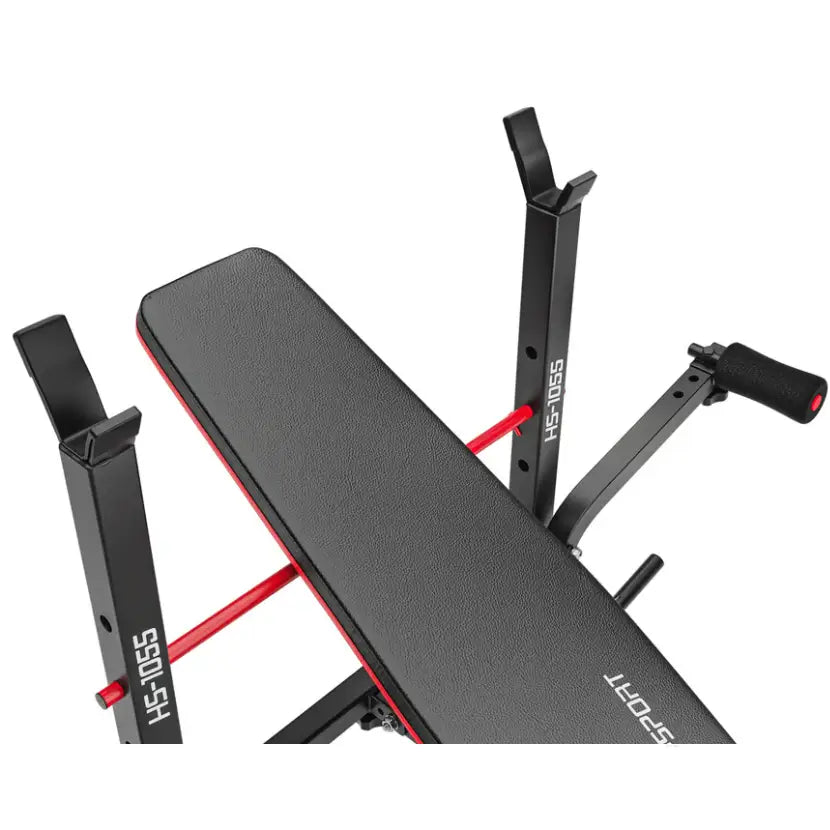 Treningsbenk med vektstangsett, sort kunstskinn med rød kant, skrå overblikk og synlig justeringspinne.