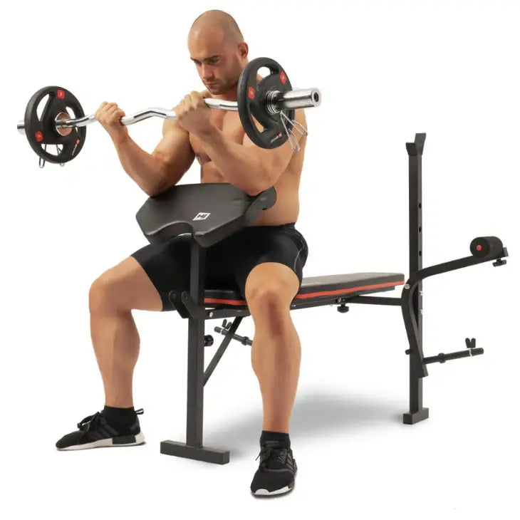 Treningsbenk med vektstangsett, mann utfører bicepscurl med EZ-stang og vektplater, skrå front.