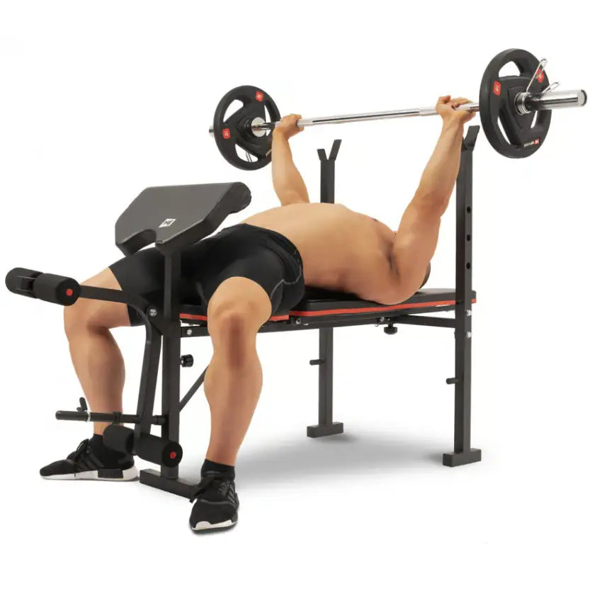Treningsbenk med vektstangsett, sidevisning av mann som gjør benkpress på svart og rød benk.