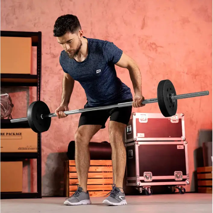 Treningsbenk med vektstangsett, mann i bøyet posisjon løfter svart stang med vektskiver, sidevisning.