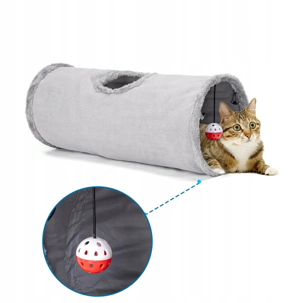 Tunnel for katt i lysegrå plysj, sett fra siden med katt inni og hengende rød-hvit ball i åpningen.
