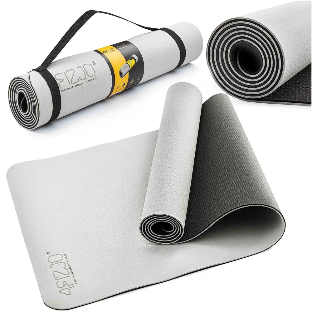 Tykk yogamatte i lys grått skum, vist utrullet og sammenrullet med bærestropp og mørk underside.