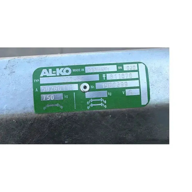 Aksling for tilhenger, nærbilde av grønt og sølvfarget metallskilt med tekniske data på metallrør.