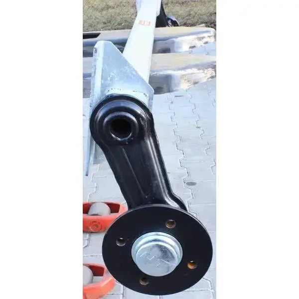 Aksling tilhenger Knott VG7, nærbilde av svart metallarm med rund ende og bolthull mot betongheller.