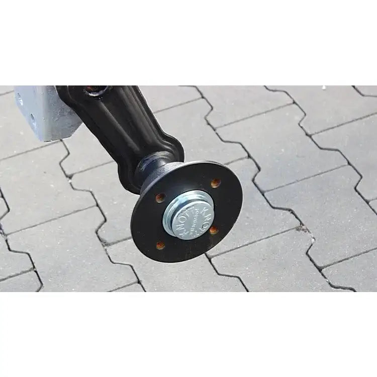 Aksling tilhenger Knott VG7-L, skråvisning av sort flens med fire bolthull og sentrert sølvbolt mot steinbakgrunn.