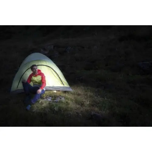 Utendørslampe LED OLI, sterkt lys som lyser opp grønt telt og person ved inngangen i mørket.