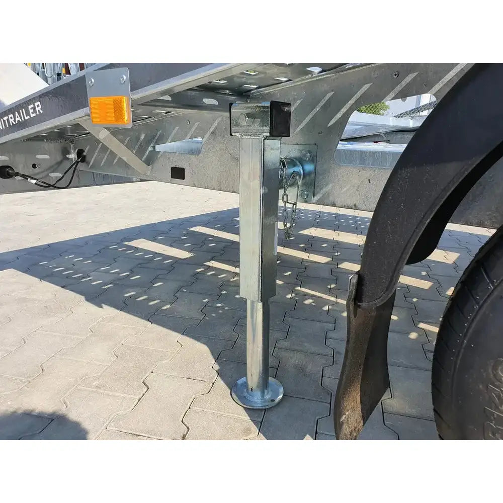 Uttrekkbar støtte for tilhenger, sidevisning med rund fotplate, sveiv og montering pü grütt understell over brostein.