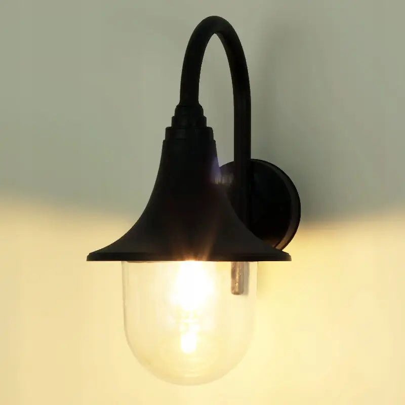 Utvendig vegglampe i sort metall med buet arm og tent glasskuppel, montert på lys vegg.