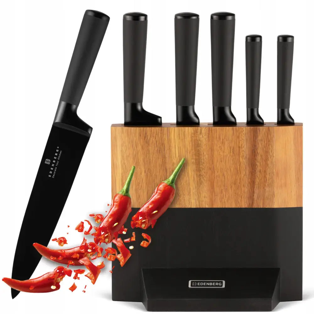 Knivsett med fem svarte kniver i blokk av lyst tre og sort, én kniv skjærer røde chilipepper.