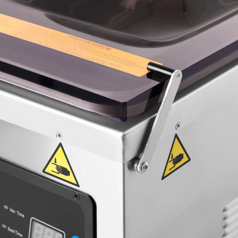 Vakuumkammermatemaskin, nærbilde av rustfritt hjørne med gjennomsiktig lokk og gule advarselsmerker.