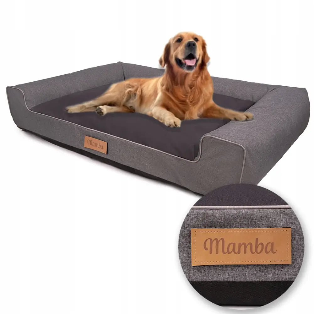 Vannavstøtende XXL hundeseng sofa i grått med mørk pute, Mamba-skinnlapp og langhåret hund som hviler.