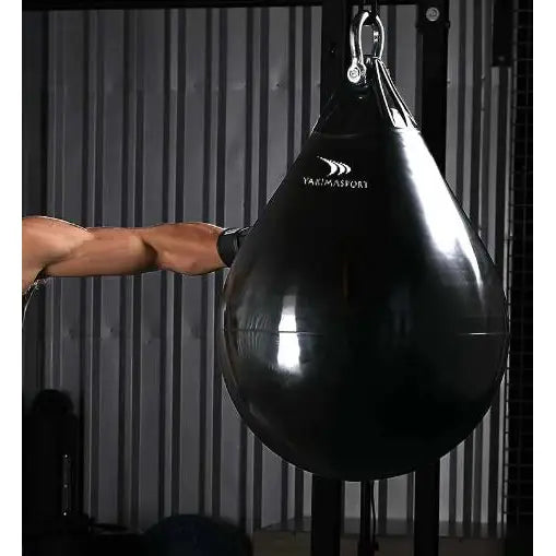 Vannfylt boksesekk Aqua Bag S, dråpeformet sort sekk i bruk med boksehanske foran metallvegg.
