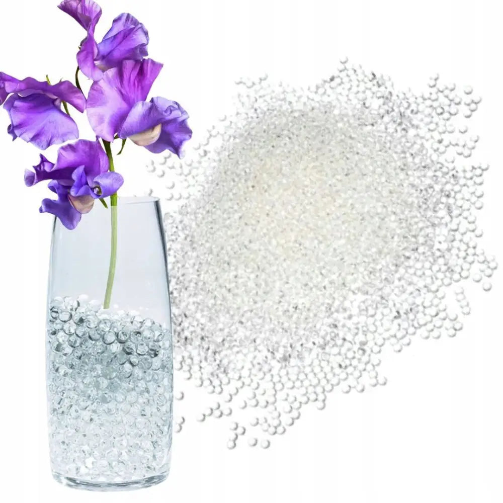 Vannperler til planter, klare hydrogelkuler i glassvase med lilla blomster og tørr haug ved siden av.