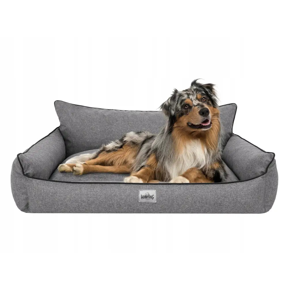Vanntett hundeseng sofa XXL i grått stoff, sett forfra med en hund som hviler mot de høye kantene og synlig logo.