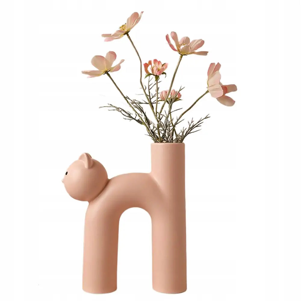 Vase i kattform, lyserosa keramikk med stiliserte detaljer, fylt med lyserosa blomster, sidevisning.