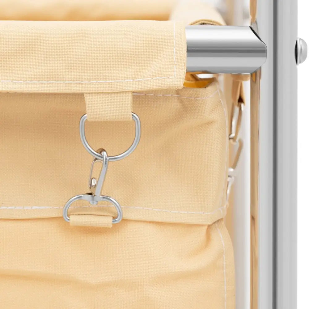 Vaskeriservice vogn, nærbilde av beige pose festet til metallramme med sølvfarget krok- og ringløsning.