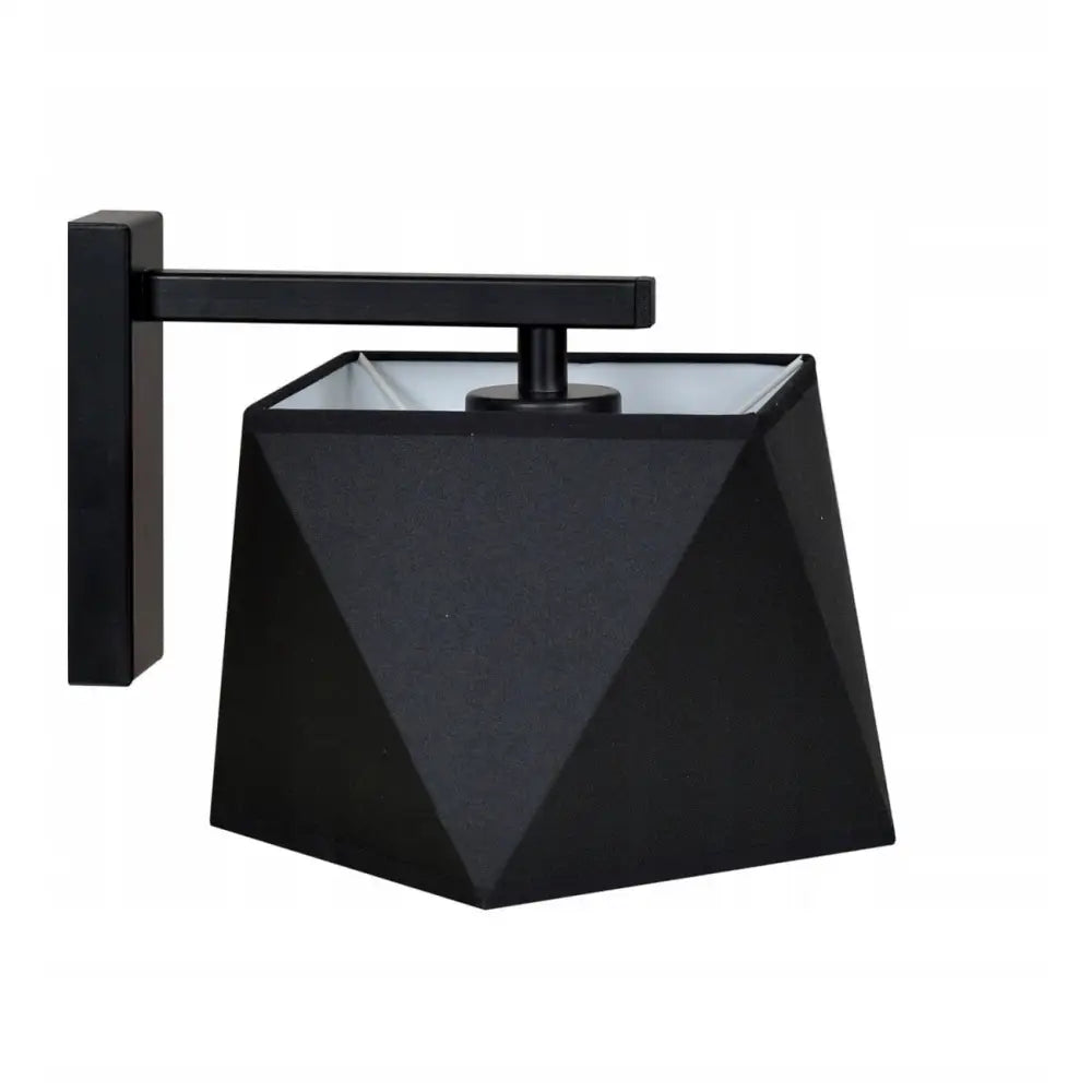 Vegglampe i sort metall, sidevisning med geometrisk diamantmønstret skjerm mot lys bakgrunn.
