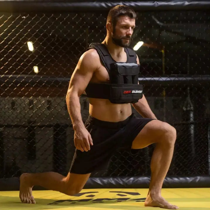 Vektvest 20kg på mann i treningsposisjon, sideprofil, justerbare stropper synlige i treningsbur med gult gulv.