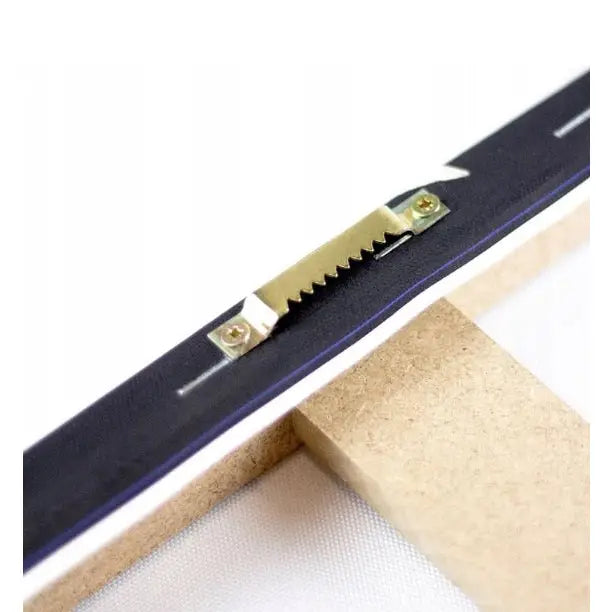 Ramme i lyst tre med taggete metalloppheng, nærbilde av opphengsbøyle og skruer bak på lerretsbildet.