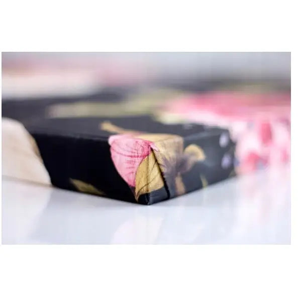 Verdenskart svart og gull lerretsbilde, nærbilde av hjørnet med rosa og gule blomster på mørk bakgrunn.