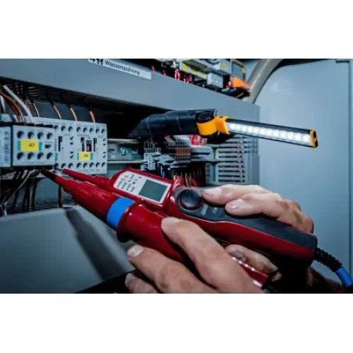 Verkstedlampe LED SANSA 400A lyser opp elektrisk koblingsskap mens måling utføres med digitalt instrument.