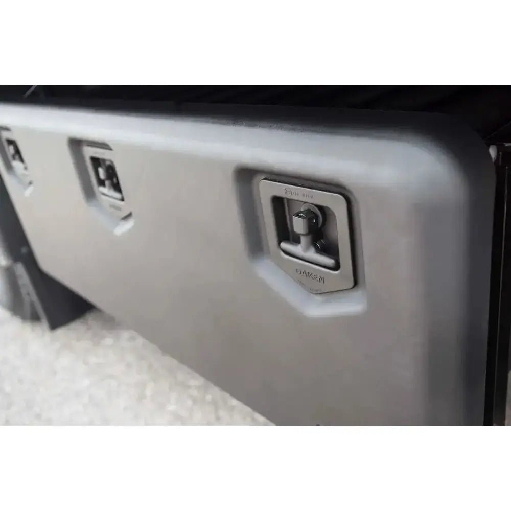 Verktøykasse Daken Welvet, skråvisning av grå hardplastskuff med metallhåndtak og lås på høyre side.