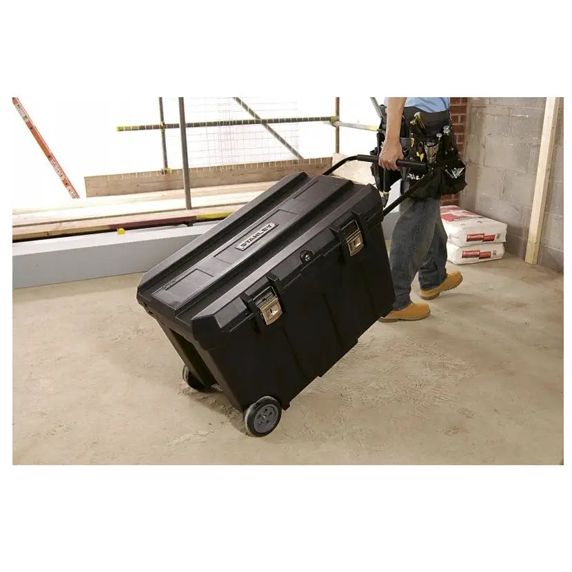 Verktøykasse Kombi fra Stanley, sort plastmodell med hjul og metallspenner, trekkes over byggeplass.