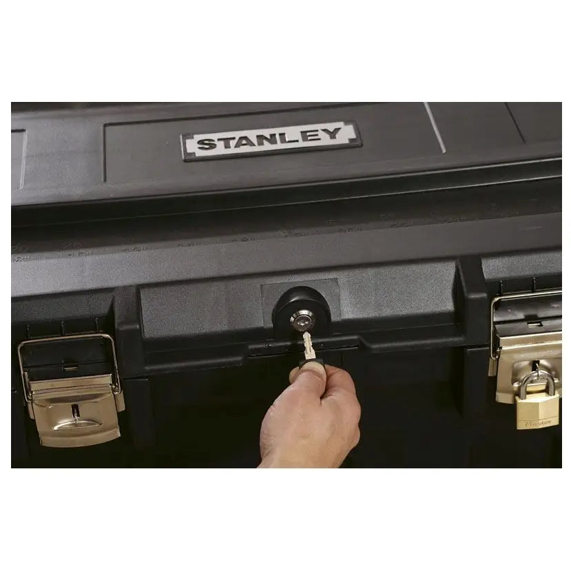 Verktøykasse Kombi 189L Stanley, nærbilde av hånd som låser metallås på svart plastkasse.