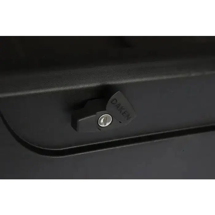 Verktøykasse med håndtak, nærbilde av sort plasthåndtak med DAKEN-logo og metall nøkkellås på mørkt underlag.