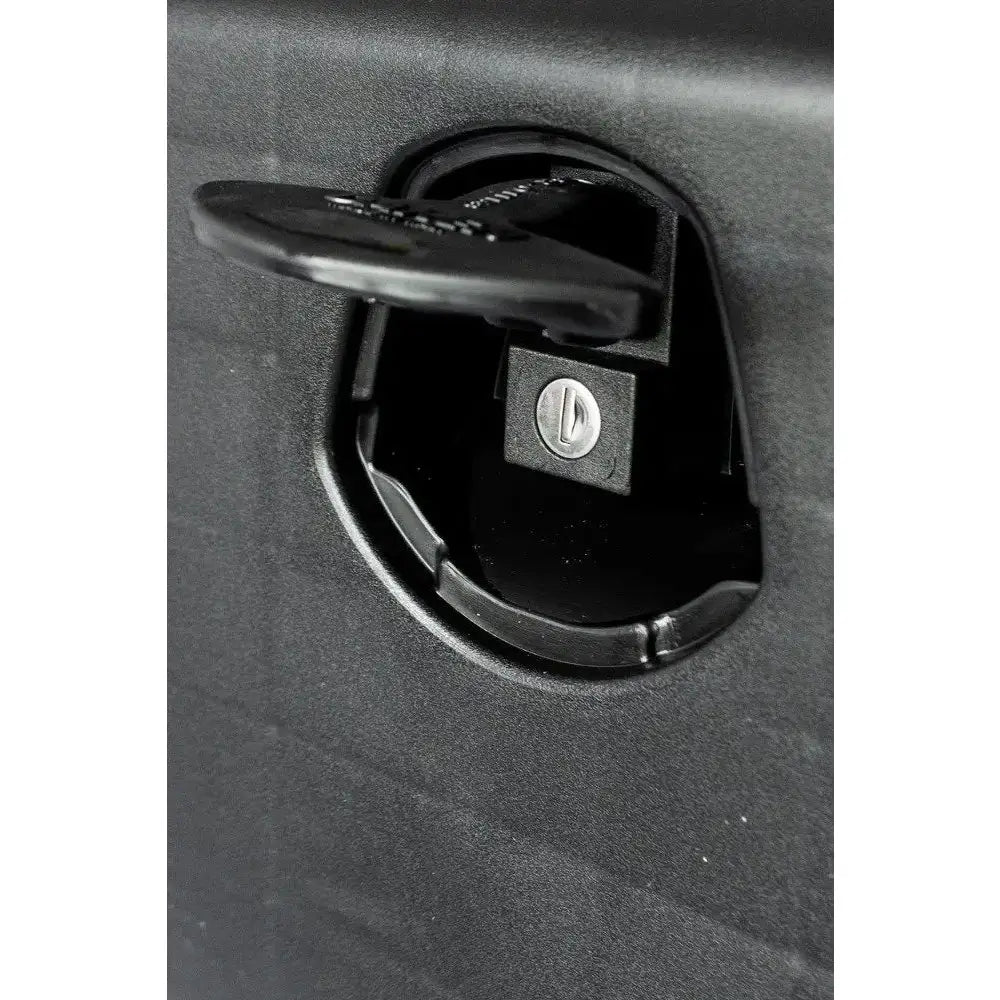 Verktøykasse med håndtak, detaljert sidebilde av sort plastlås med nøkkelinnsats mot strukturert overflate.