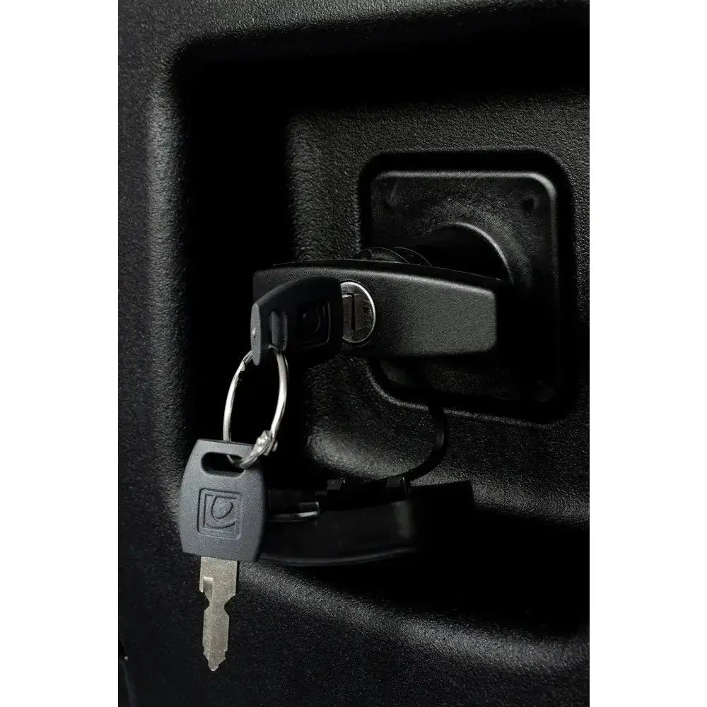 Verktøykasse med håndtak, detalj av sort nøkkel i lås med vrider på ru sort overflate, to nøkler i ring.