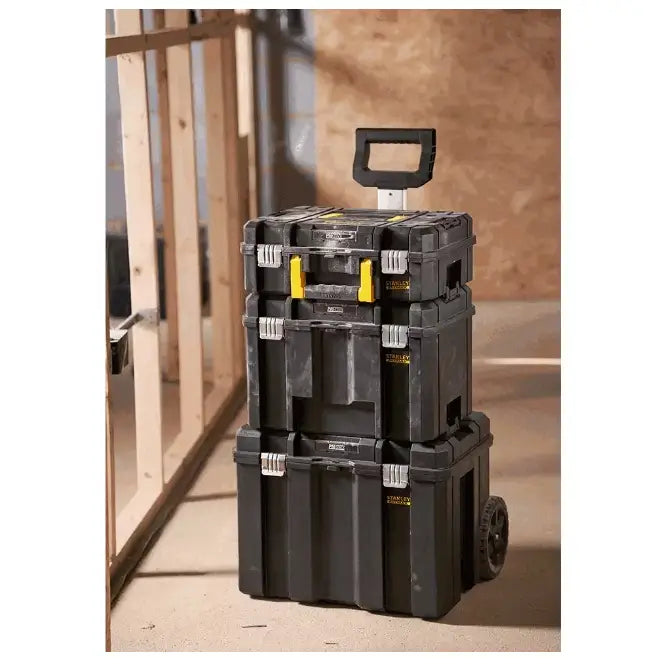 Verktøykasse med organizer på hjul fra Stanley, tre sorte bokser stablet med håndtak, sett fra skrå vinkel på byggeplass.