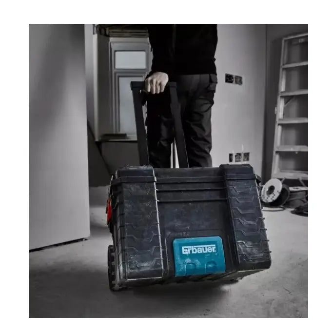 Verktøykasse på hjul Solid, frontvisning mens den trilles av en person i arbeidsklær i et lyst rom.