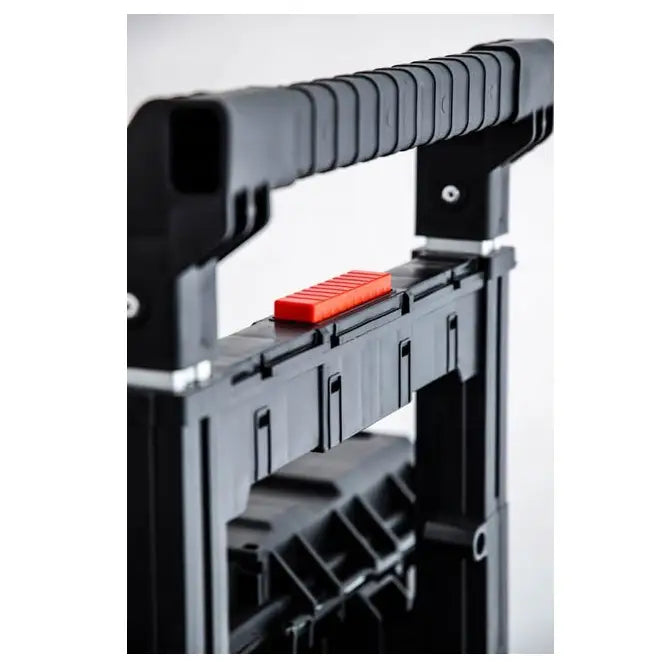 Verktøykasse Qbrick One Cart, nærbilde av sort håndtak med riller og synlig rød låseknapp fra skrå vinkel.