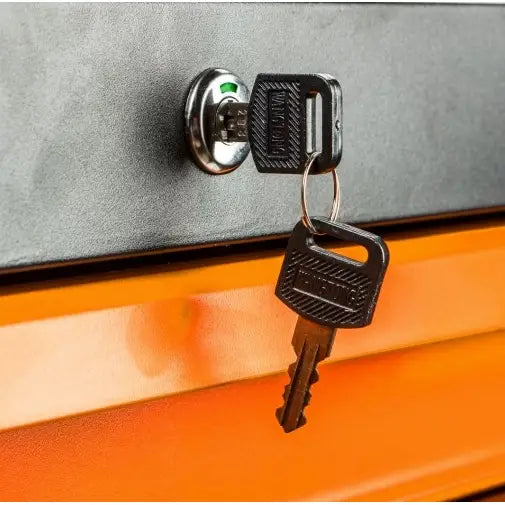 Verktøyskap med oransje front, nærbilde av rund sølvlås med to svarte nøkler hengende fra låsen.