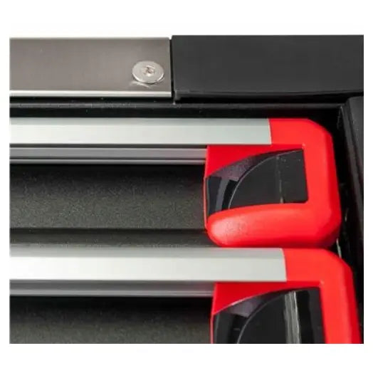 Verktøyvogn, nærbilde av to metallstenger med røde og svarte ender i sort eske, sett ovenfra.