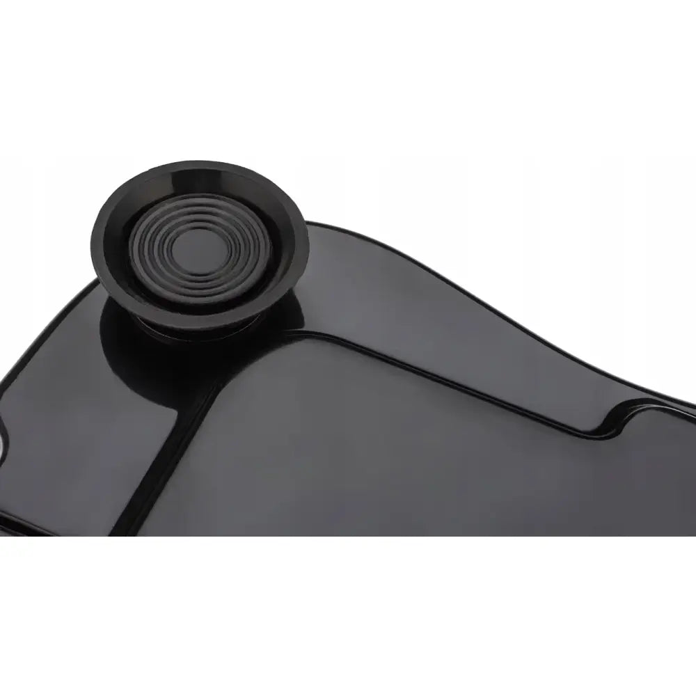 Vibrasjonsplattform, nærbilde av blank svart overflate med rund, riflet detalj i hjørnet.