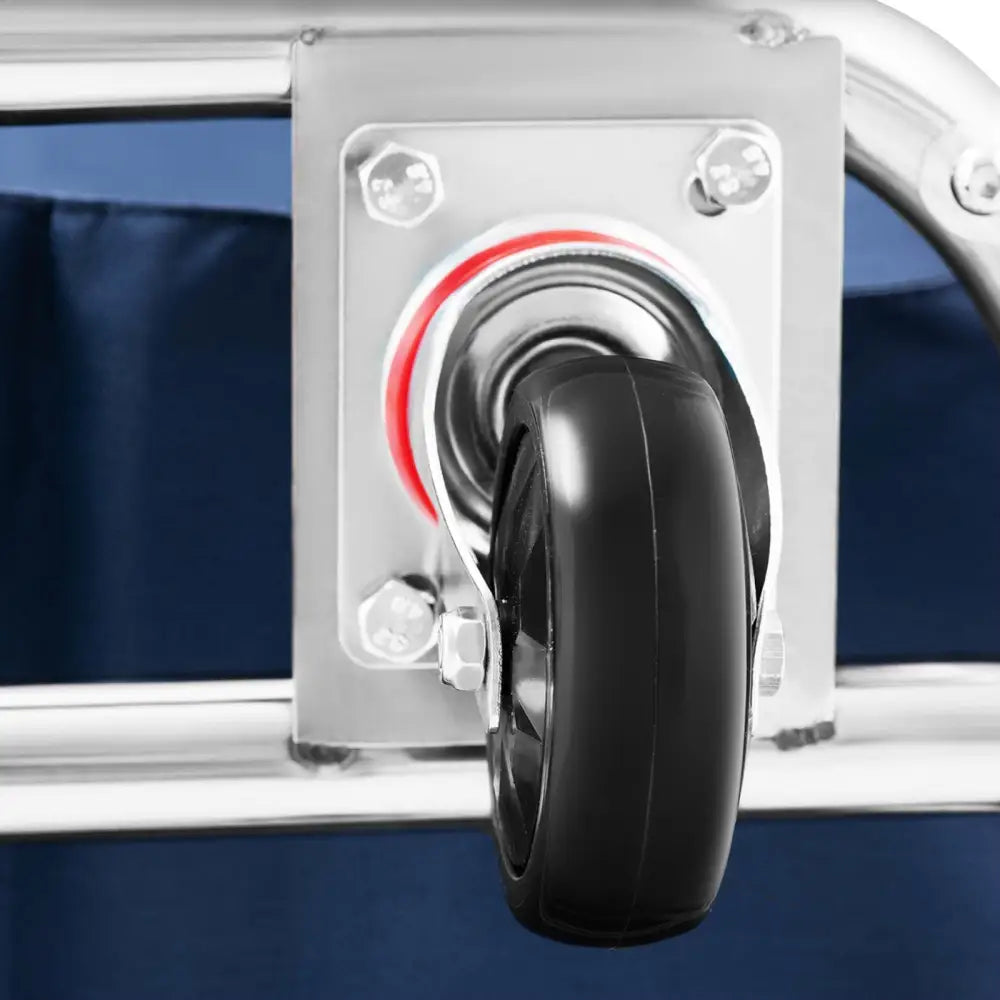 Sort plasthjul på metallramme for hotellvogn, med synlige bolter og blått stoff i bakgrunnen.