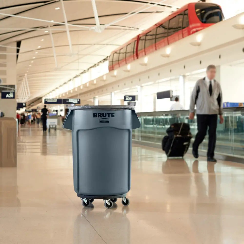 Vognbase til BRUTE-beholder, grå plastdolly med hjul, forfra i travel terminal med bagasje.