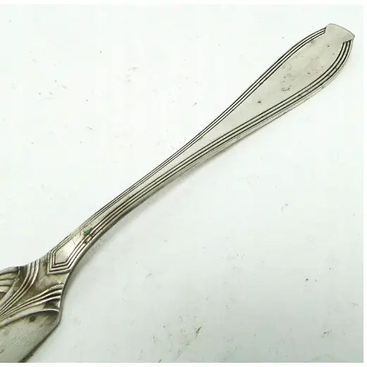 WMF Jugendstil fiskekniv, sidevisning av håndtak med dekorative graveringer og avrundet ende mot lys bakgrunn.