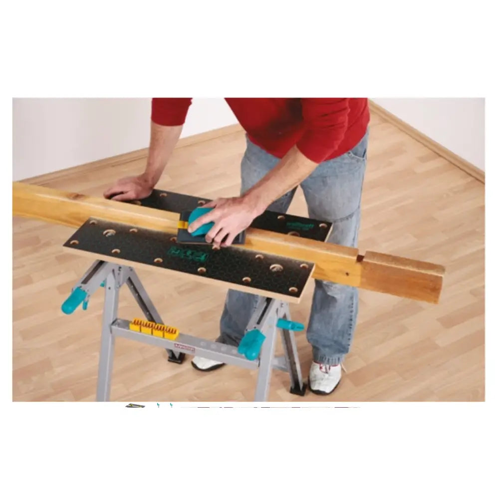 Wolfcraft arbeidsbenk Master 200 sett ovenfra, med treplanke festet og en person som pusser overflaten.