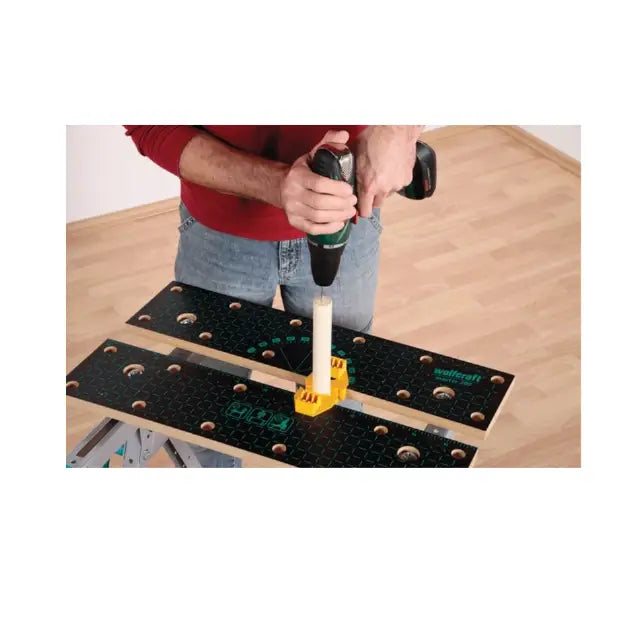 Wolfcraft arbeidsbenk Master 200 i bruk, trepinne festet med gul holder mens det bores med batteridrill.